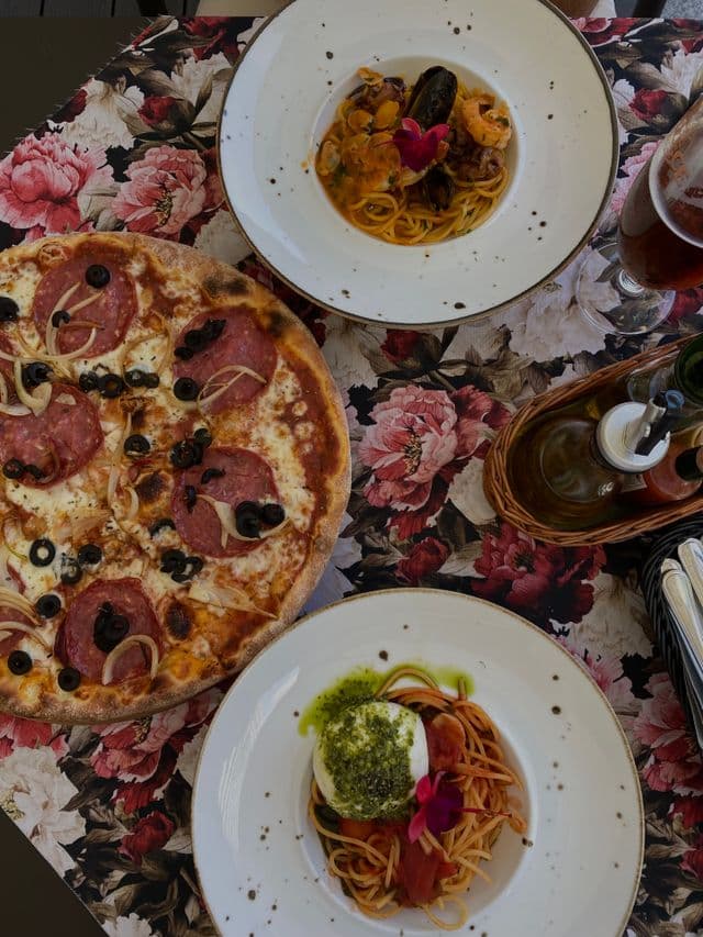 Pizza et pâtes aux fruits de mer sur nappe fleurie